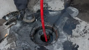 Local plumber clearing blocked drain with professional plumbing equipment