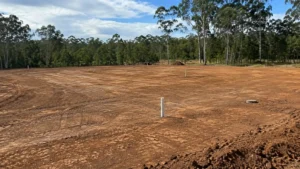 Earthmoving site preparation on an acreage property in South East Queensland with a levelled dirt pad and visible pipe markers