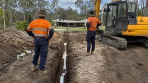 Septic excavation and drainage trenching on a residential acreage site with pipework installed beside an excavator