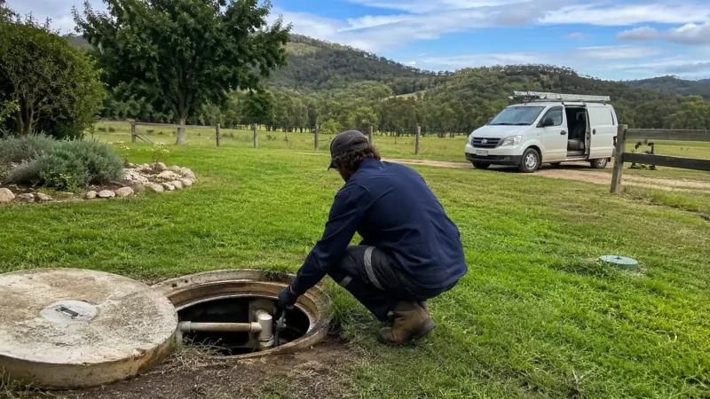 Plumber inspecting an open septic tank on a rural acreage property in the Scenic Rim, Queensland.